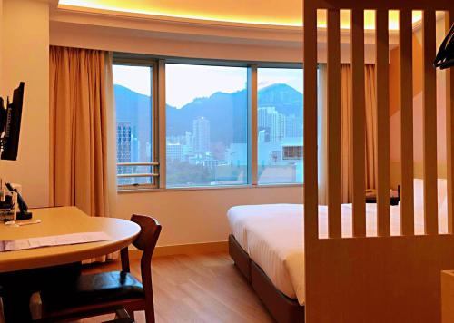 um quarto de hotel com uma cama, uma secretária e uma janela em South Pacific Hotel em Hong Kong