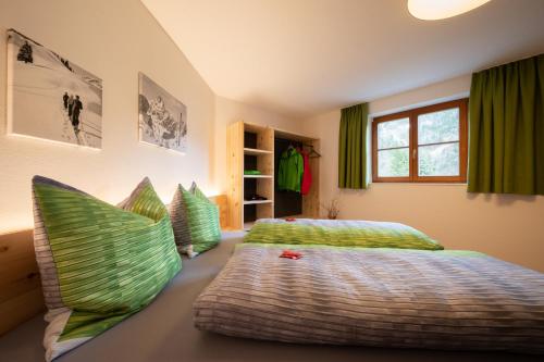 Schlafzimmer mit einem Bett mit grüner Bettwäsche und Kissen in der Unterkunft Ferienwohnung Carmen Schuchter in Vandans