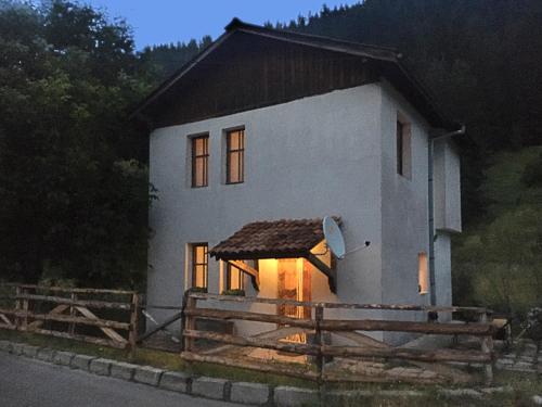 a small white house with a fence in front of it at Къща край реката - Триград in Trigrad