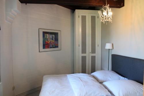 a bedroom with a bed with white sheets and a chandelier at Urlaubsmühle Fortuna St. Peter-Ording in Borsthusen