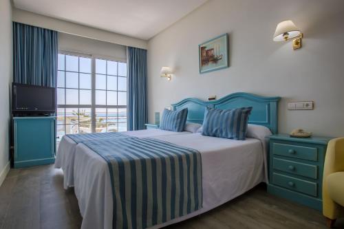 a bedroom with a bed with blue furniture and a television at Hotel Villa de Laredo in Fuengirola