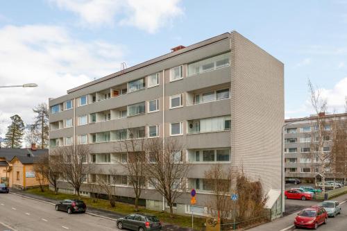 ein Apartmenthaus mit Autos auf einem Parkplatz in der Unterkunft Kotimaailma Kuopio in Kuopio