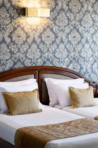 a bedroom with two beds and a wall with wallpaper at Mediterranean Palace in Thessaloniki