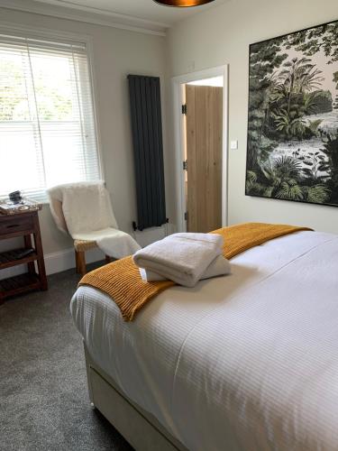 a bedroom with a bed and a chair and windows at THE LAZY LION in Milford on Sea