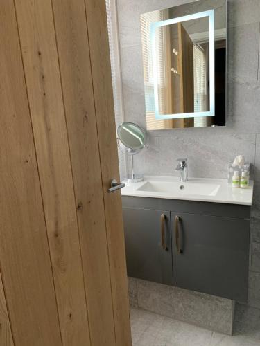 La salle de bains est pourvue d'un lavabo et d'un miroir. dans l'établissement THE LAZY LION, à Milford on Sea