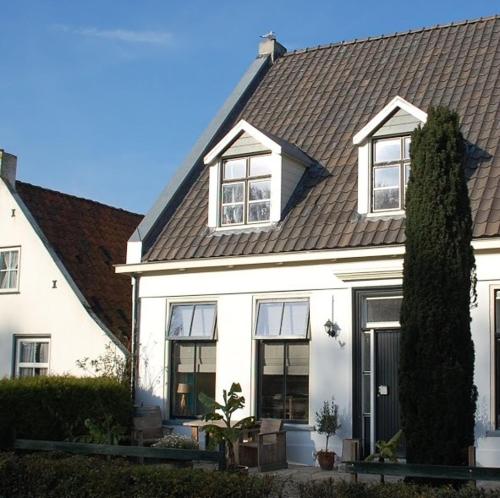een wit huis met een zwart dak bij De Salon op Schiermonnikoog in Schiermonnikoog
