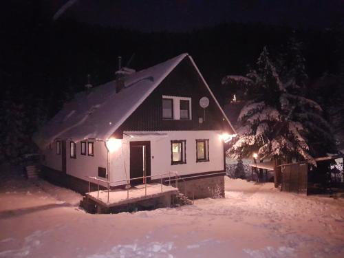 a house in the snow at night with lights at Chata Tanvaldský Špičák in Tanvald