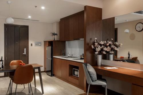 a kitchen with wooden cabinets and a table and chairs at DHTS Business Hotel & Apartment in Ho Chi Minh City