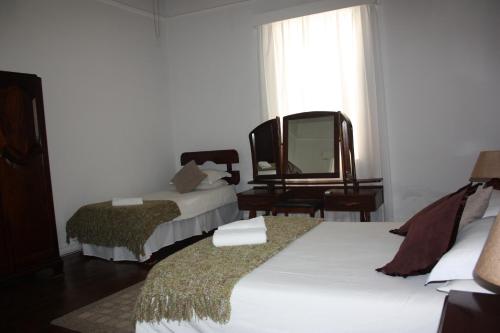 a hotel room with two beds and a mirror at Karoopark Guest House in Graaff-Reinet
