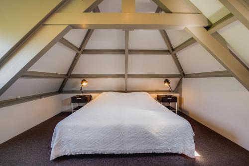 a bedroom with a white bed in a attic at Villa Magnolia in Oostkapelle