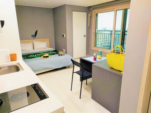 a small room with a bed and a desk and a kitchen at ARA Palace Hotel in Jeju