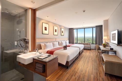 um quarto de hotel com uma cama grande e um lavatório em Kokoon Hotel Banyuwangi em Banyuwangi