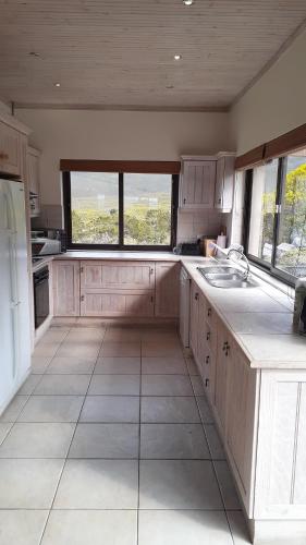 a large kitchen with white cabinets and a large window at Barton Luxury Villas in Botrivier
