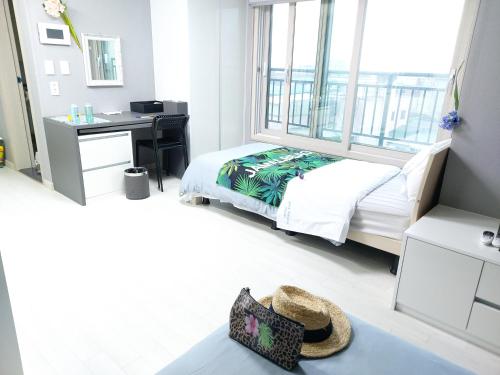 a bedroom with a bed and a desk and a window at ARA Palace Hotel in Jeju