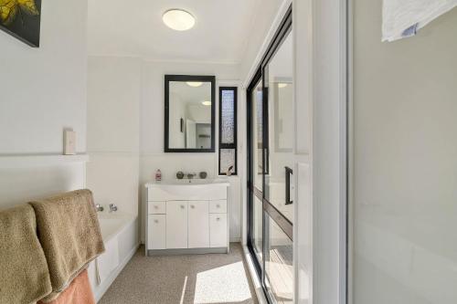 a bathroom with a tub and a sink and a mirror at Rotorua redwood retreat in Rotorua