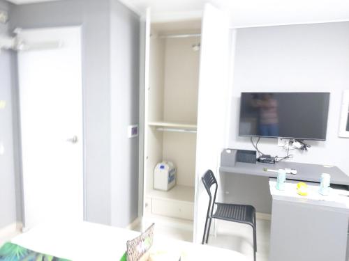 a living room with a desk and a tv at ARA Palace Hotel in Jeju