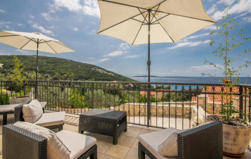 a patio with chairs and tables and an umbrella at Hacienda Babina in Miholašćica