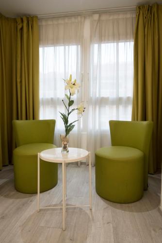 two green chairs and a table and a vase with a flower at Rambla Alicante Contactless in Alicante