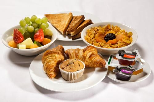 a table with three plates of food and bowls of fruit at ibis Aberdeen Centre – Quayside in Aberdeen