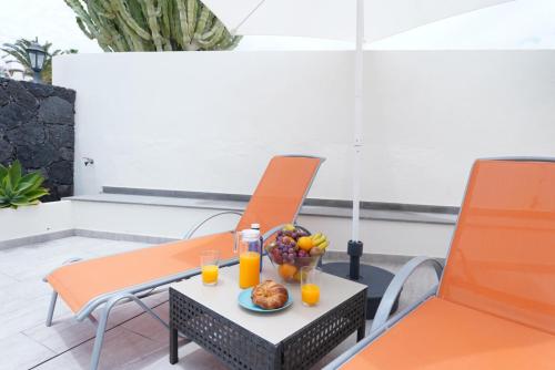 コスタ・テギセにあるLuxury Villa sea front Costa Teguiseの椅子2脚、テーブル(フルーツ、オレンジジュース付)