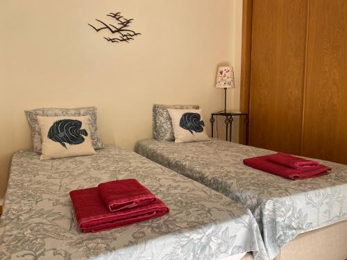 two beds in a room with red towels on them at Poço do Bispo 28 in Tavira
