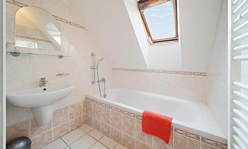 een badkamer met een wastafel, een bad en een spiegel bij Penzion pivovarská restaurace Moravia in Brno