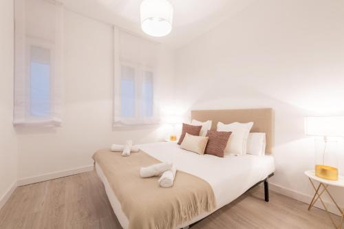 Un dormitorio blanco con una cama grande con toallas. en Bright and modern- 2 bedrooms 1bathroom- MintyStay - Bocángel en Madrid