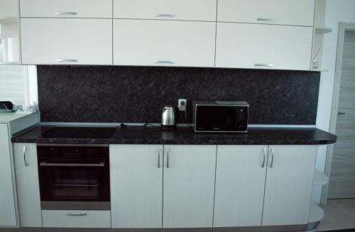 a kitchen with white cabinets and a black counter top at Стаи за гости ValenDa in Kirkovo