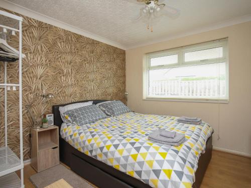 a bedroom with a bed and a window at Fern Hill Cottage in Llanfairpwllgwyngyll