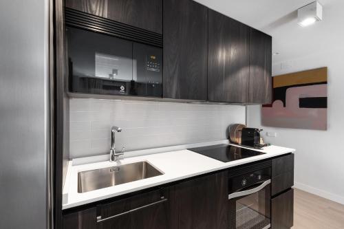 una cocina con armarios de madera y fregadero en Luxury and cozy- 2 bedrooms 2 bathrooms -MintyStay- Herradores, en Madrid