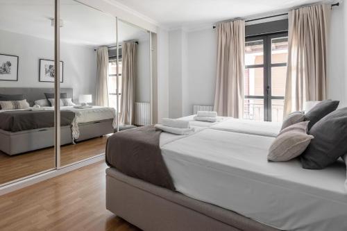 een slaapkamer met 2 bedden en een grote spiegel bij Luxury and cozy- 2 bedrooms 2 bathrooms -MintyStay- Herradores in Madrid