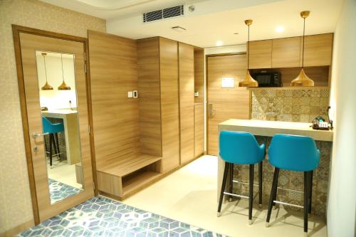 a kitchen with wooden cabinets and blue bar stools at Holiday Inn Gurugram Sector 90 by IHG in Gurgaon