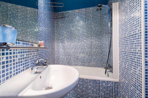 ein blau gefliestes Bad mit einem Waschbecken und einer Badewanne in der Unterkunft MintyStay - Hernán Cortés in Madrid