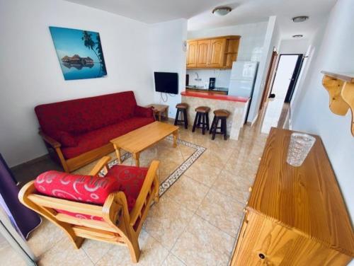 ein Wohnzimmer mit einem roten Sofa und einem Tisch in der Unterkunft Apartamentos Sandra in Playa del Ingles