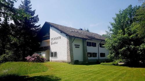 a white building with a sign on the side of it at Pension & Fewos Fuchs in Mauth