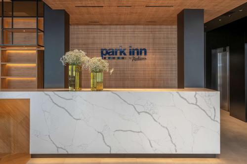 a lobby with a marble counter with flowers on it at Park Inn by Radisson Vilnius Airport Hotel & Conference Centre in Vilnius