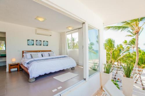 a bedroom with a bed and a balcony with palm trees at Dream Punta Cana Beachfront Apartment - 4-Bedroom Penthouse with Rooftop BBQ & Ocean Views in Punta Cana