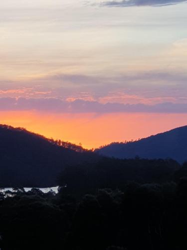 a sunset in the mountains with trees in the foreground at The Tin Dragon in Tullah