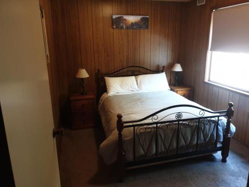 a bedroom with a bed and two night stands with two lamps at Huntinaddi Lodge in Halls Gap