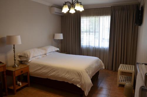 Un dormitorio con una cama grande y una ventana en Hydro Guesthouse, en Bloemfontein