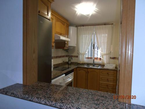 een keuken met houten kasten en een aanrecht bij Bonito apartamento en Marina D'or [1ra línea de playa] in Oropesa del Mar