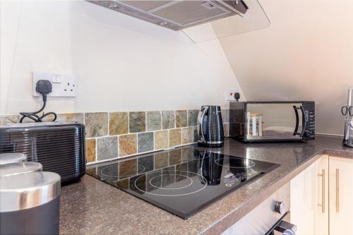 a kitchen with a stove top oven next to a microwave at Guest Homes - Hillbrook House Dwelling in Great Malvern