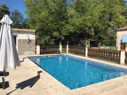 - une piscine avec un parasol à côté d'une clôture dans l'établissement Charmant T2 au calme proche centre, à Arles