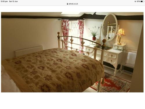 a bedroom with a bed with a dresser and a mirror at 1 The Mews Cottages in Ledbury