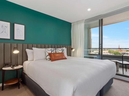 a bedroom with a large bed and a large window at The Sebel Melbourne Moonee Ponds in Melbourne