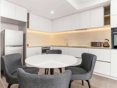 a kitchen with a white table and chairs at The Sebel Melbourne Moonee Ponds in Melbourne