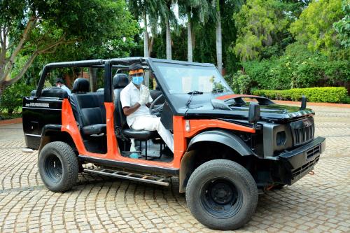 an orange jeep with two people sitting in it at Vijayshree Resort, Hampi in Hampi