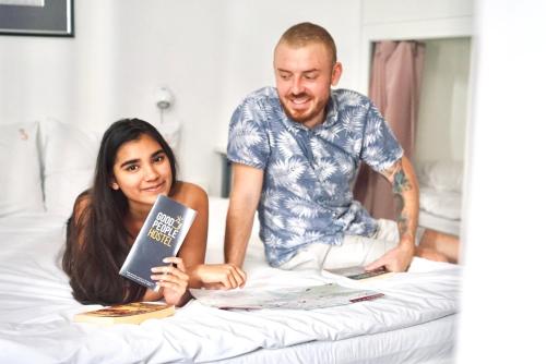 a man and woman sitting on a bed reading books at Good People Design Hostel in Belgrade