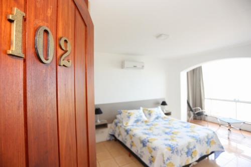 a bedroom with a bed and a wooden door at Pousada Praia Do Meio in Torres