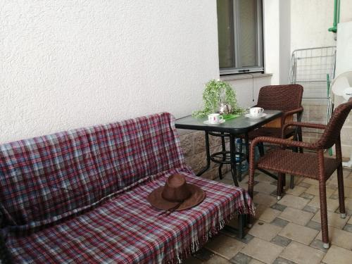 um sofá com um chapéu sobre uma mesa com cadeiras em Экономичная студия с тенистым патио вблизи пляжа em Kotor